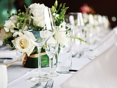 Dækket hvidt bord til fest med glas og hvide blomster
